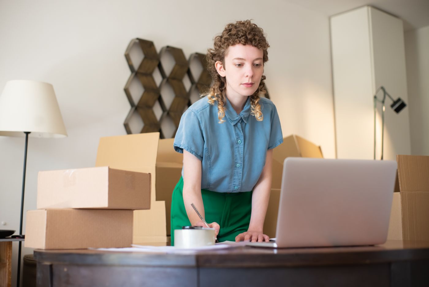 A merchandiser updating products at a laptop among parcels